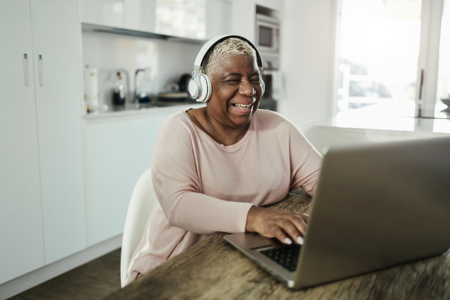 Senior woman using laptop while wearing headphones at home